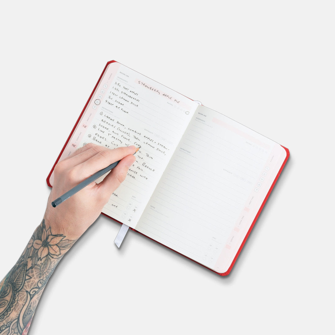 Hand writing in open Savor Recipe Journal.